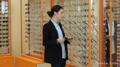 自信的女验光师与剪贴板和铅笔检查橱窗与眼镜在光学商店橱窗与眼镜在现代眼科